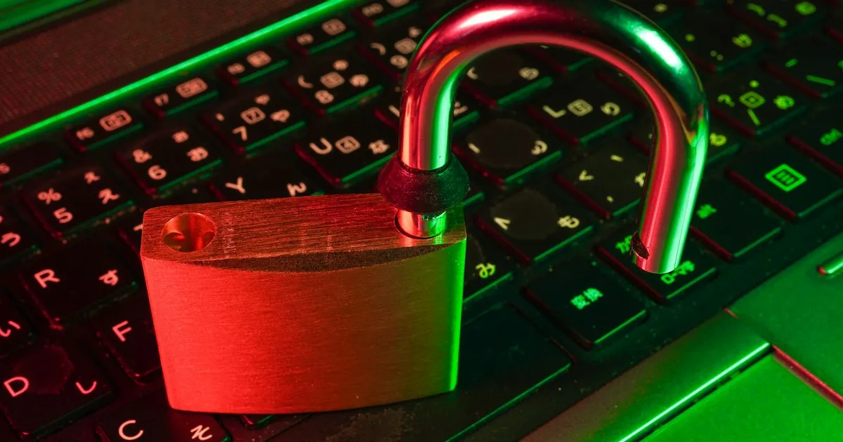 An open padlock resting on a laptop keyboard, lit in red and green